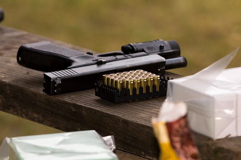 A gun and some ammo on top of a table.