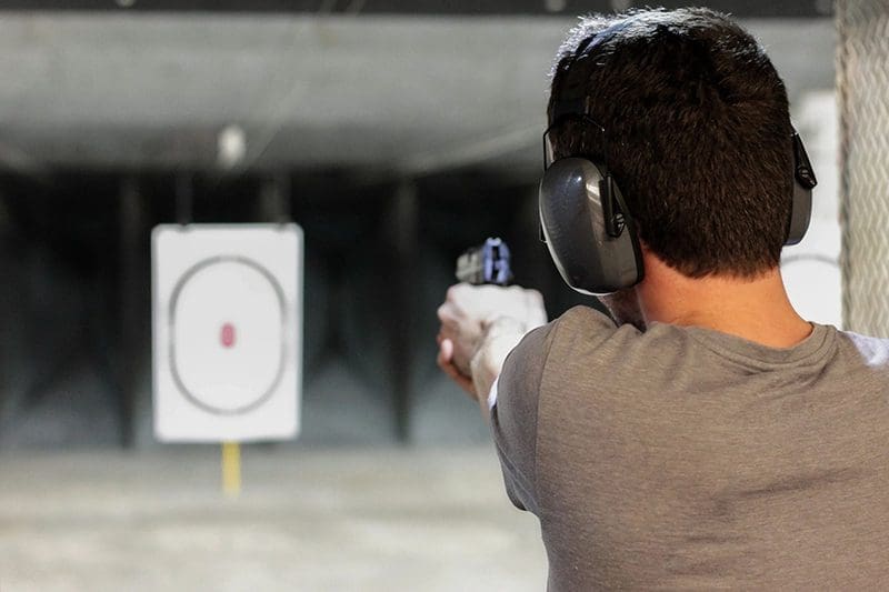 A man is aiming at an object with his gun.