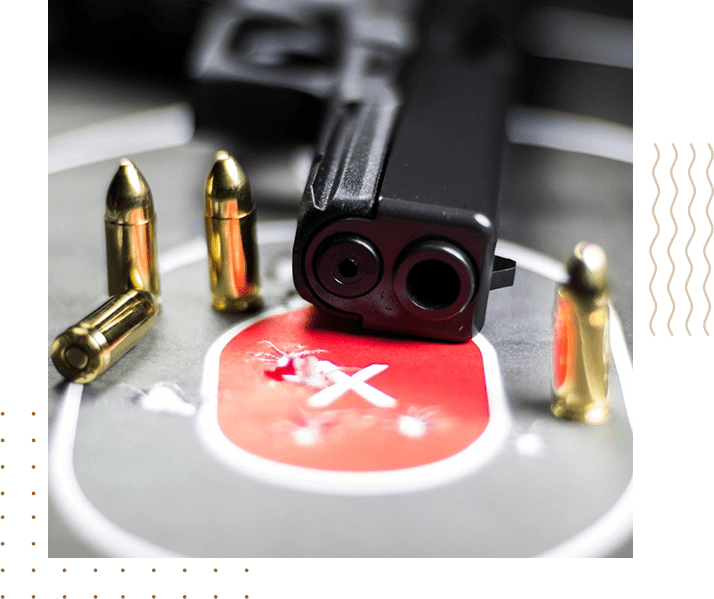 A gun and bullet holes on the floor of an indoor shooting range.