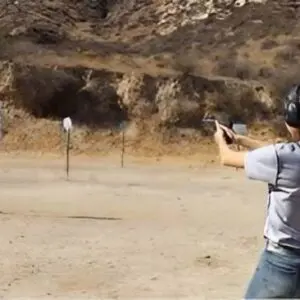 A man is shooting at a target with his gun.