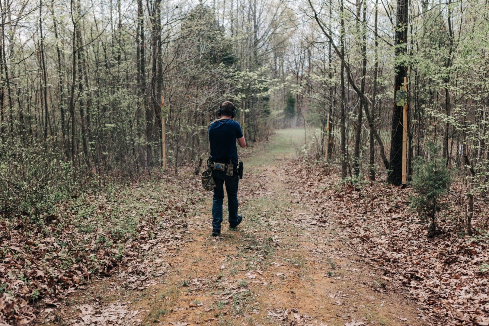 A man walking down the road in the woods.