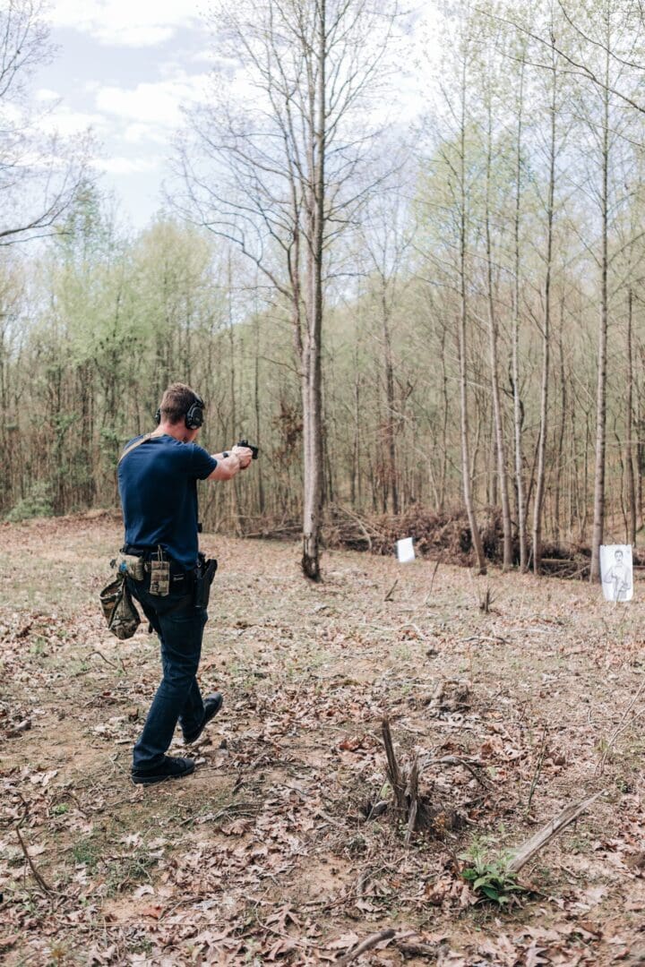 A man is shooting at an object in the woods.