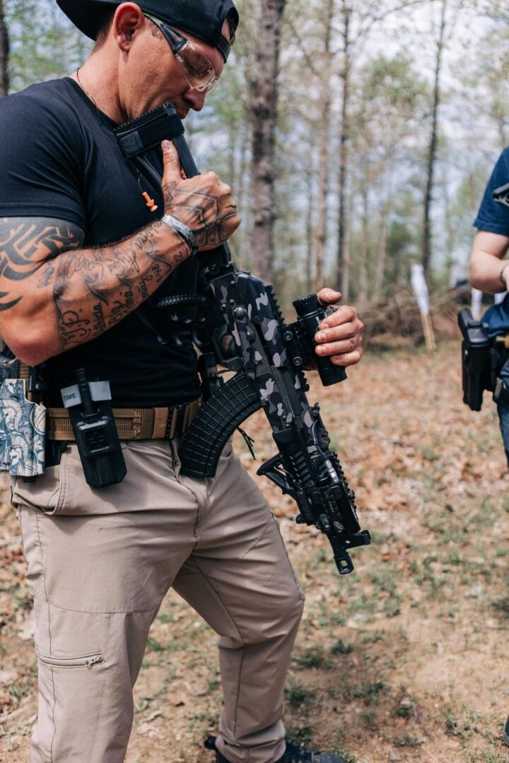 A man with tattoos holding an ar-1 5 rifle.