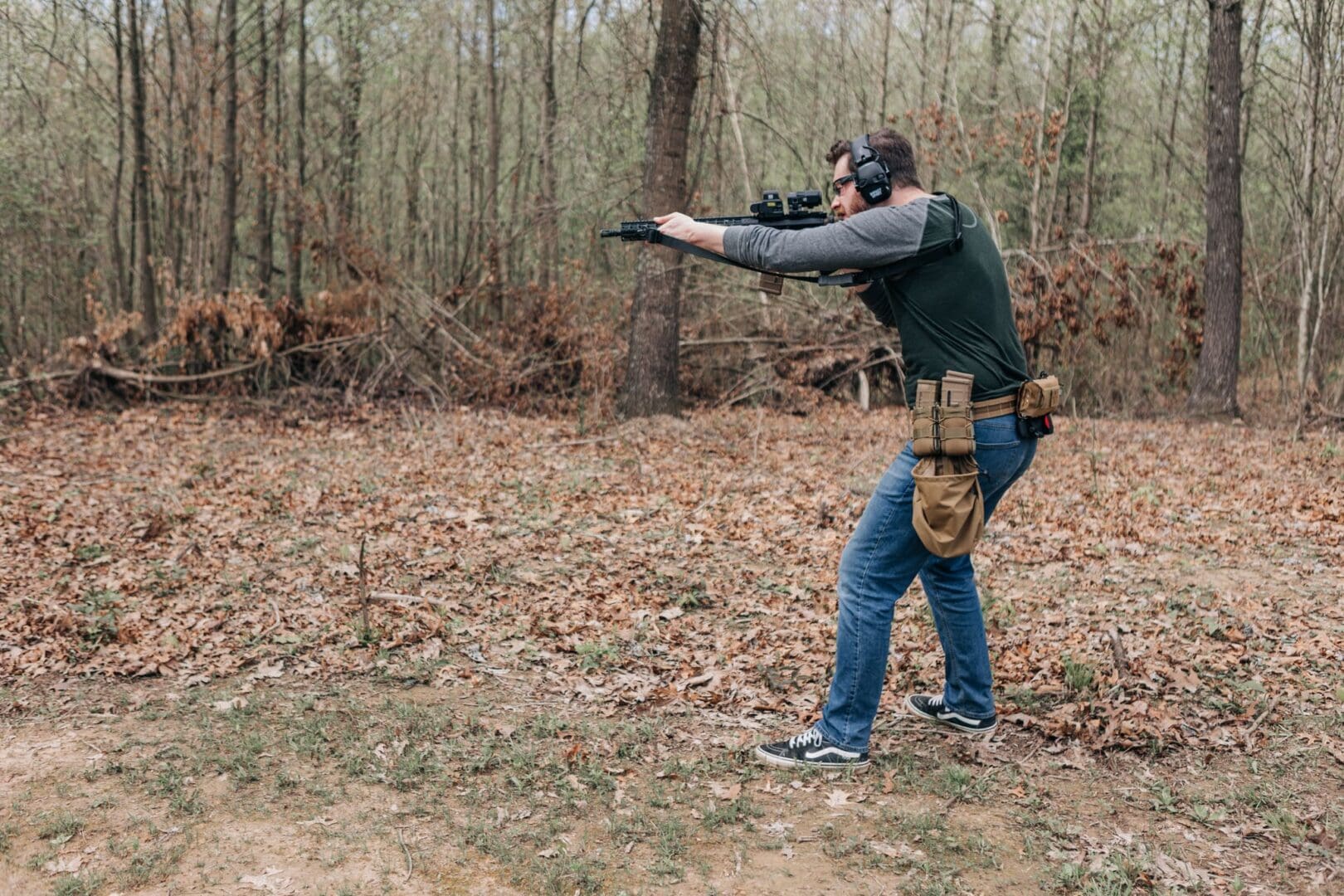 A man is shooting at something in the woods.