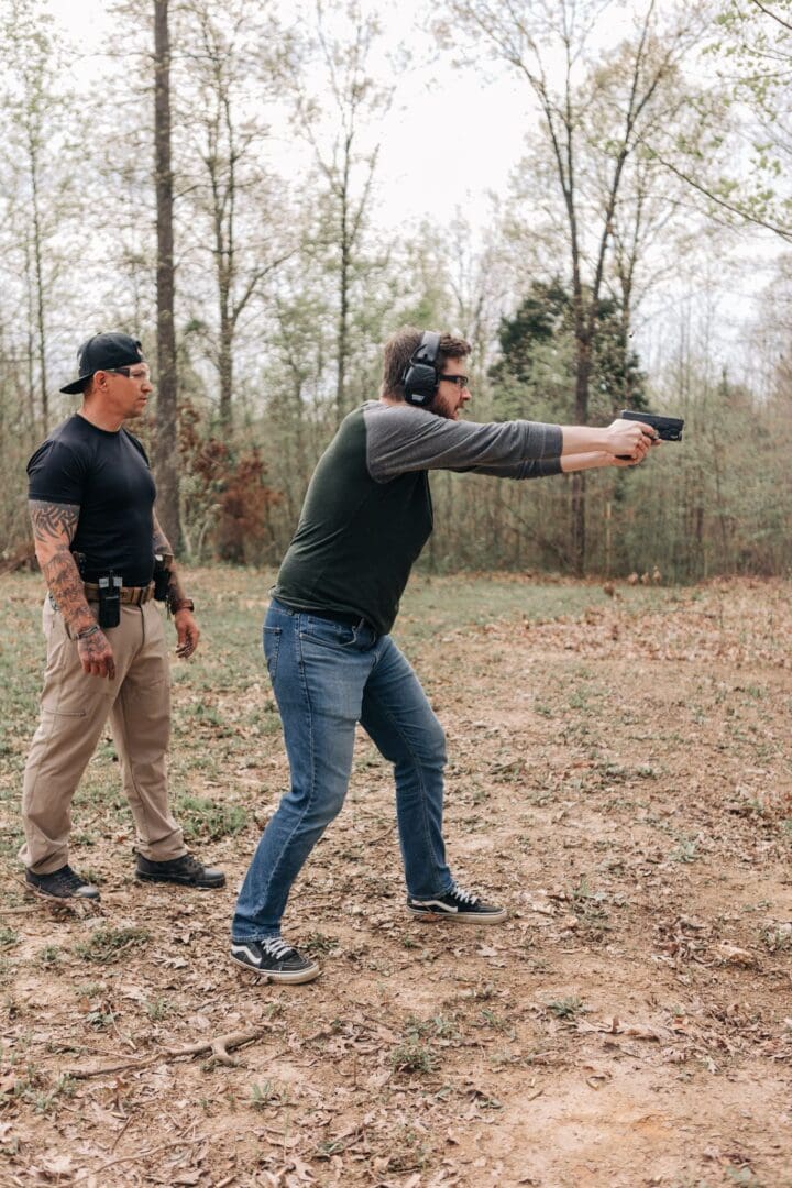 A man is holding a gun while another man watches.