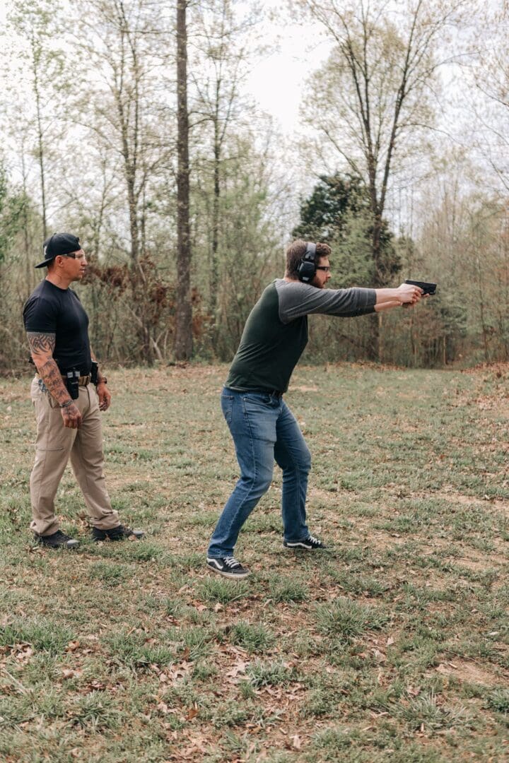 A man in black shirt holding a gun near another man.