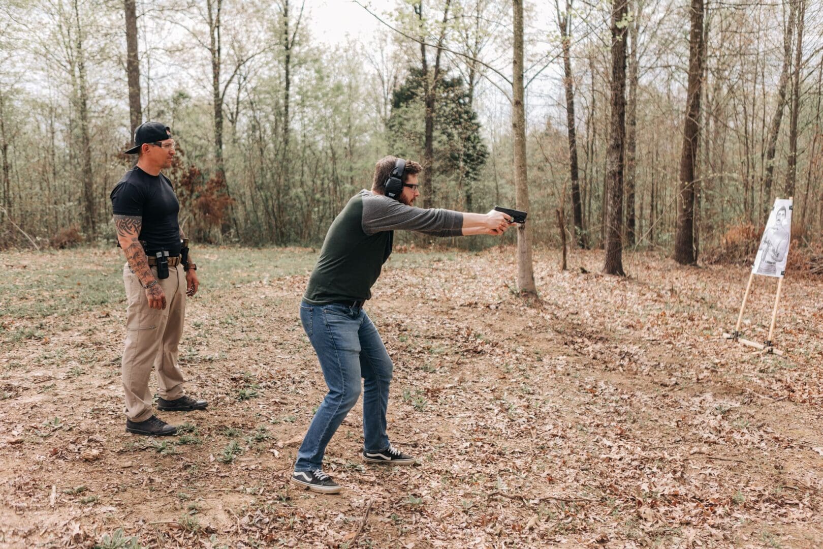 A man in the woods with a gun pointed at him.