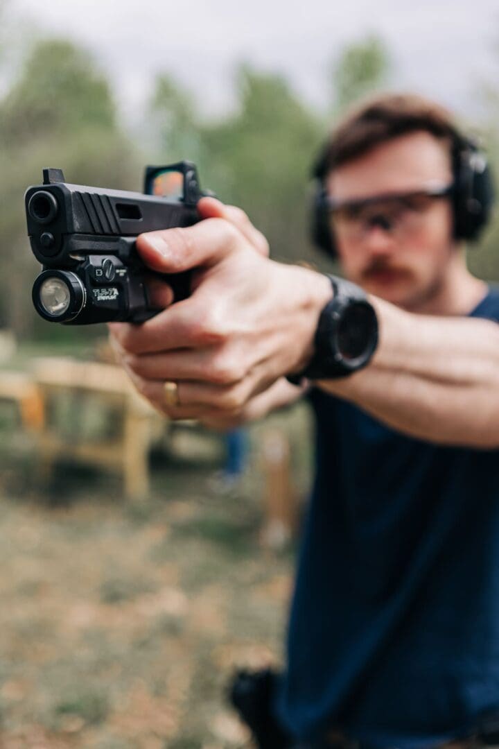 A man holding a gun with headphones on.