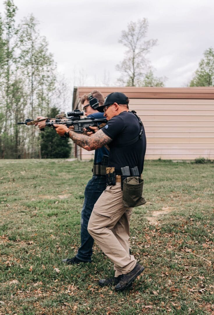 Two men in black shirts and tan pants holding guns.