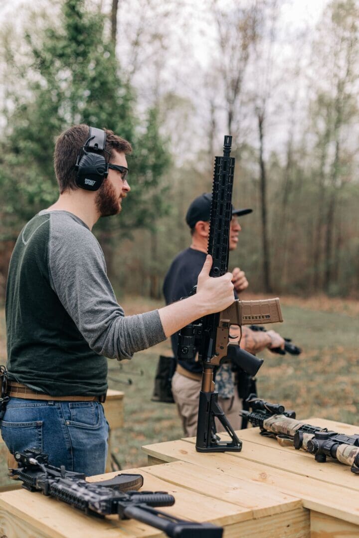 A man holding a rifle while standing next to another man.