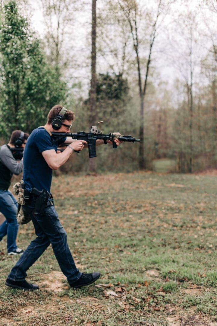 Two men are holding guns and walking in a field.