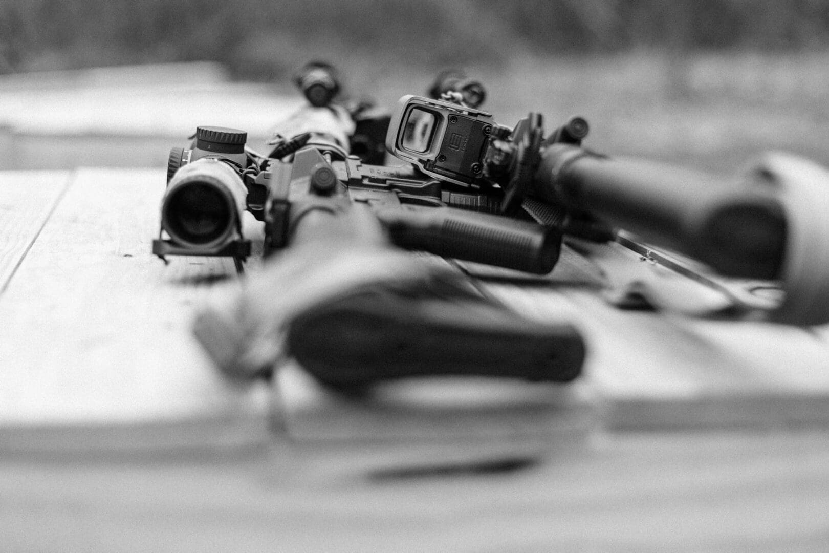 A rifle and scope laying on top of the ground.