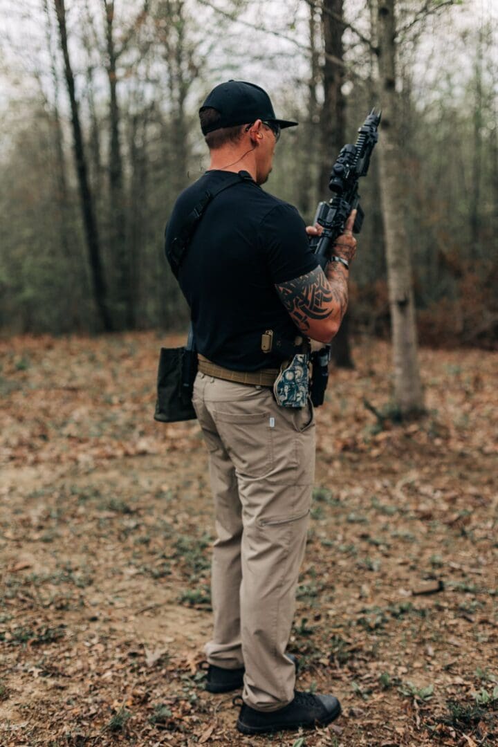 A man holding a rifle in the woods.