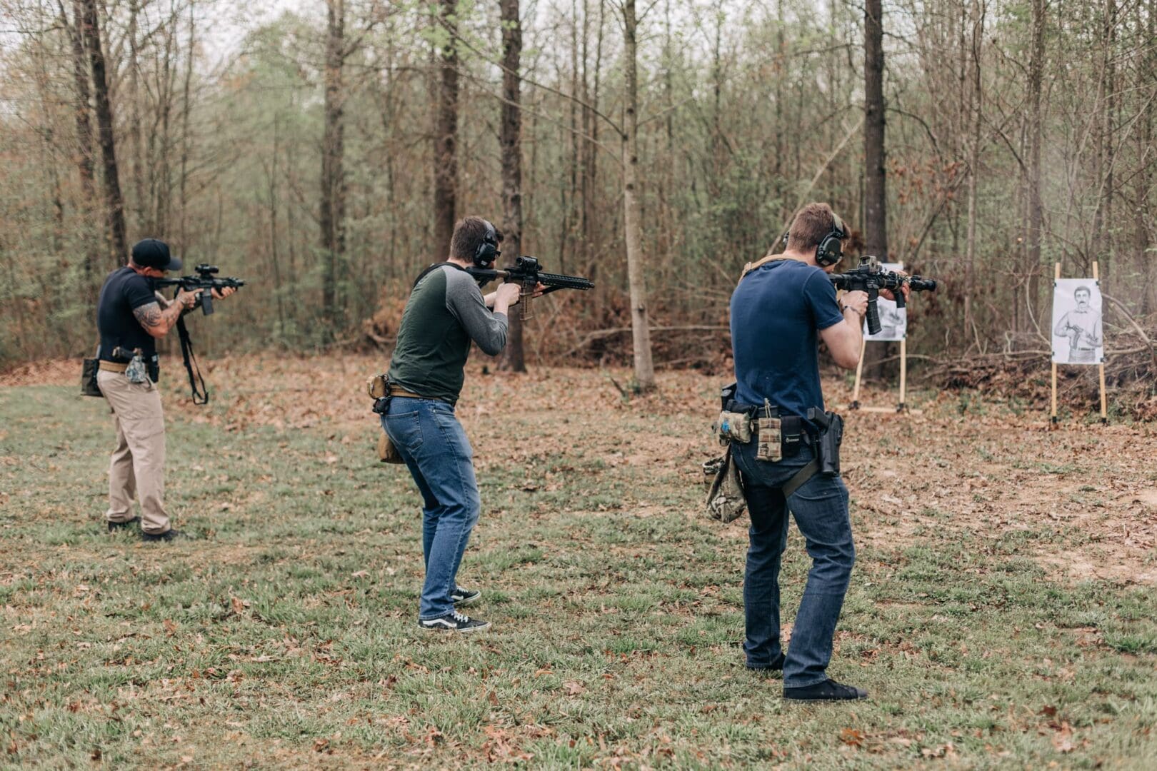 Two men are shooting guns in a field.