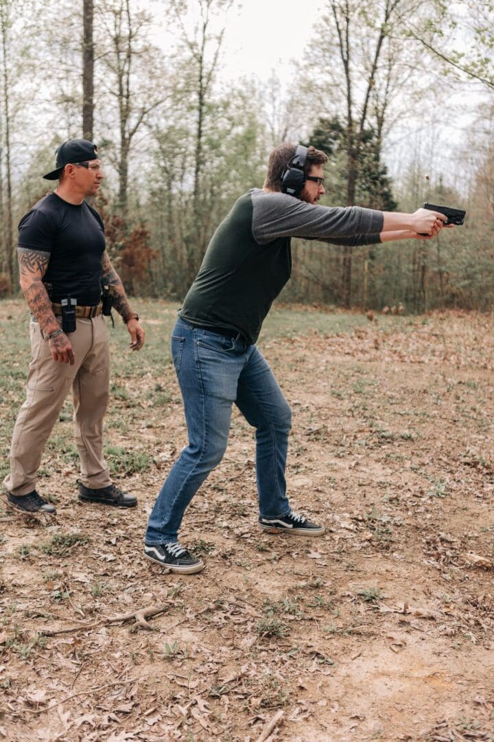 A man holding a gun in his hand while another man watches.