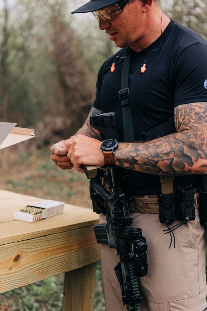 A man with tattoos holding onto some guns