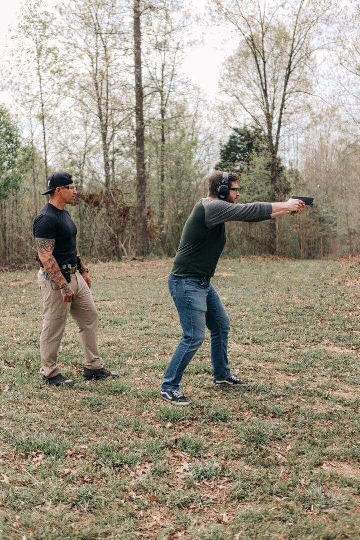 Two men are standing in a field with guns.