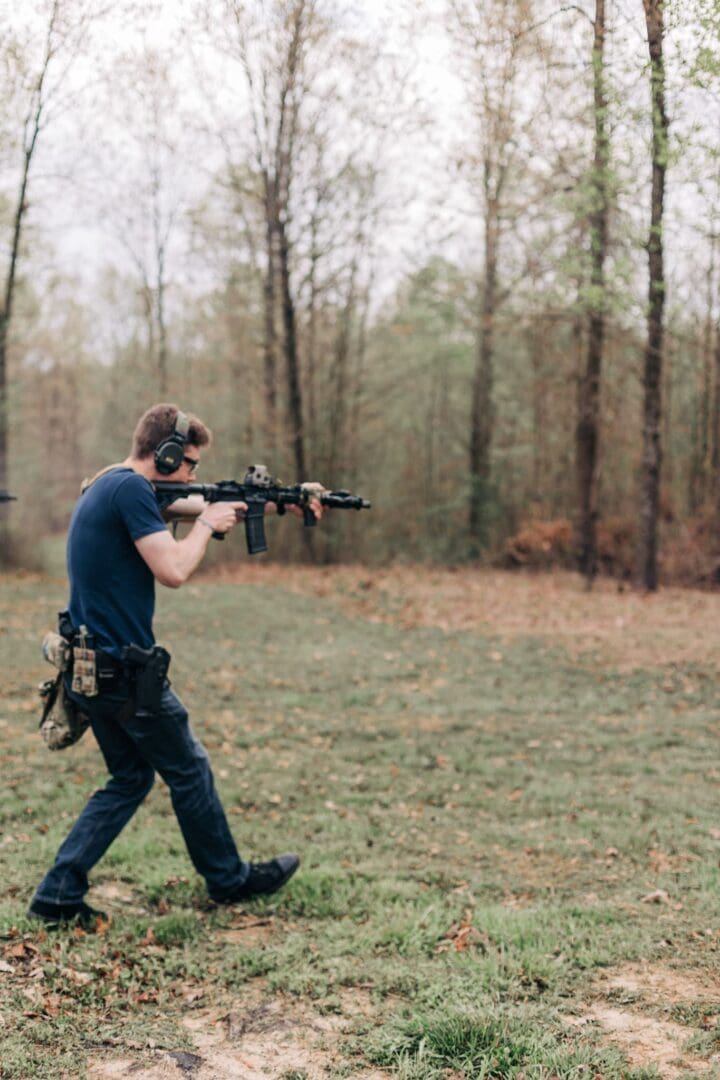 A man holding an ar-1 5 rifle while walking through the woods.