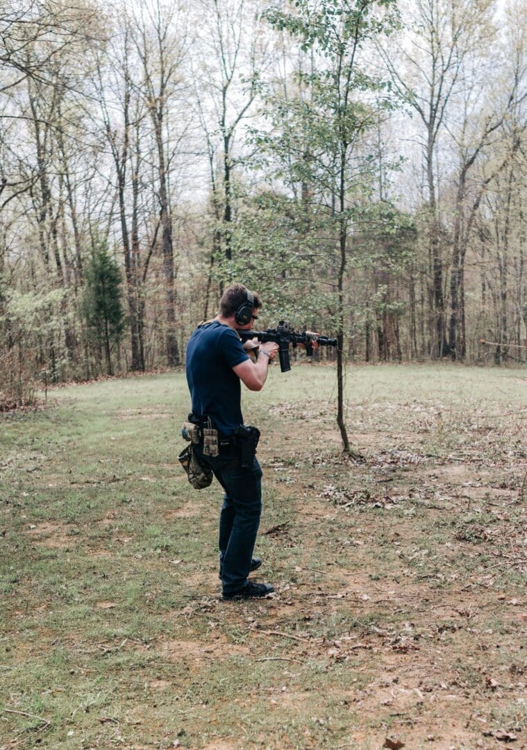 A man holding an ar-1 5 rifle in the woods.