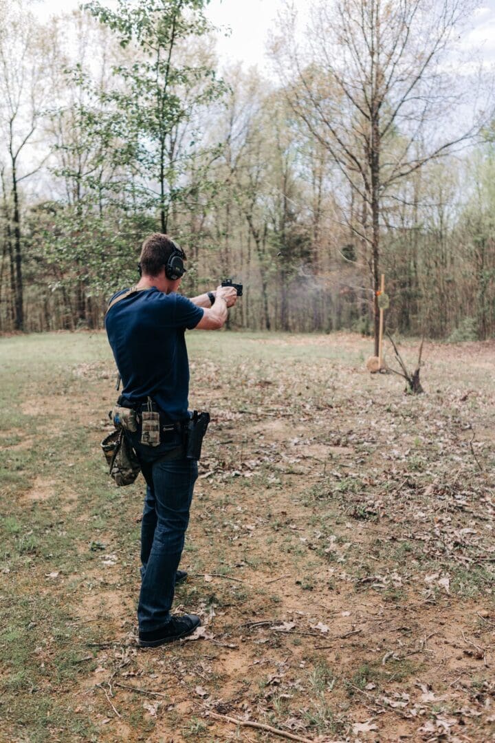 A man is shooting at something in the woods.