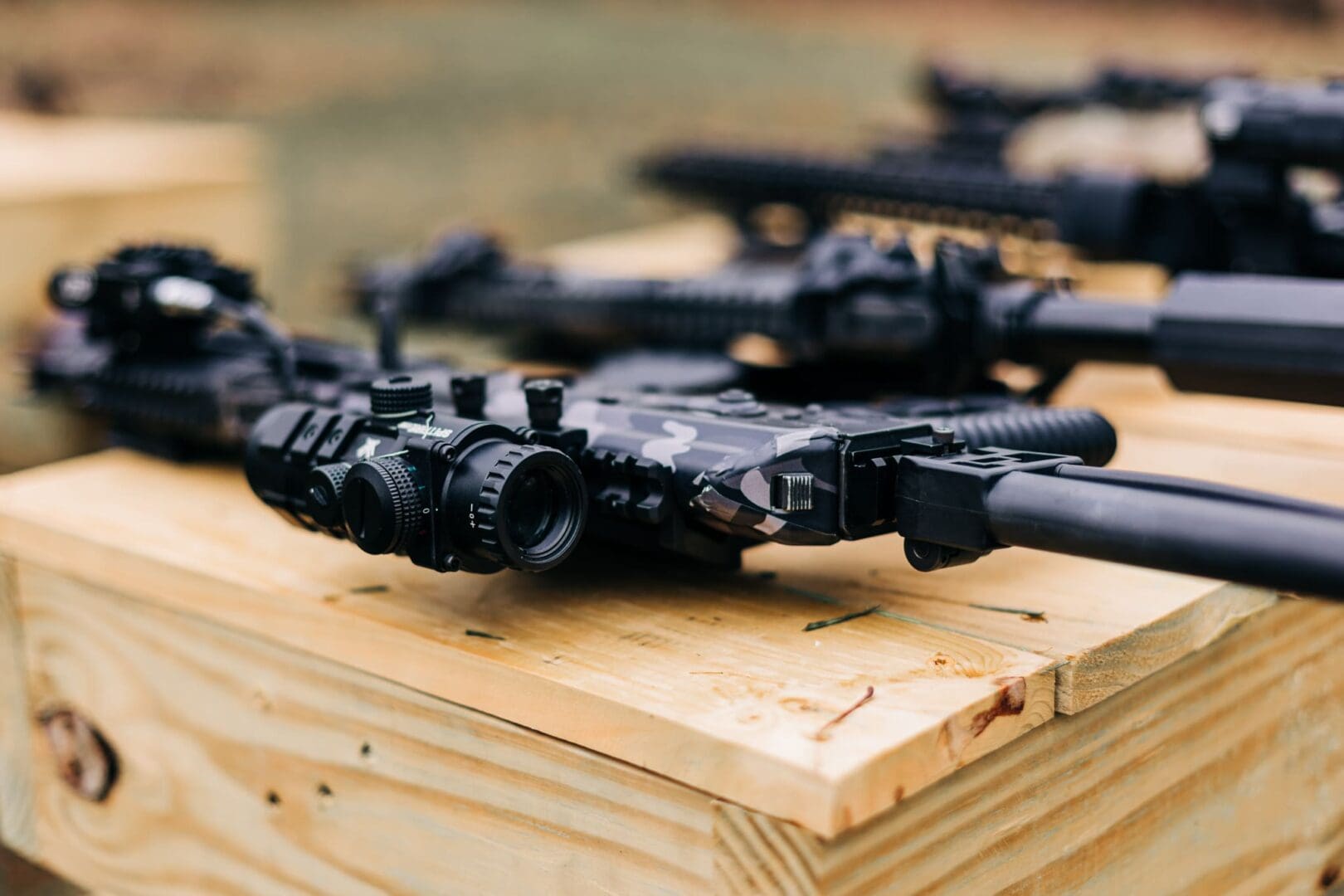 A bunch of toy guns are on top of a wooden table.