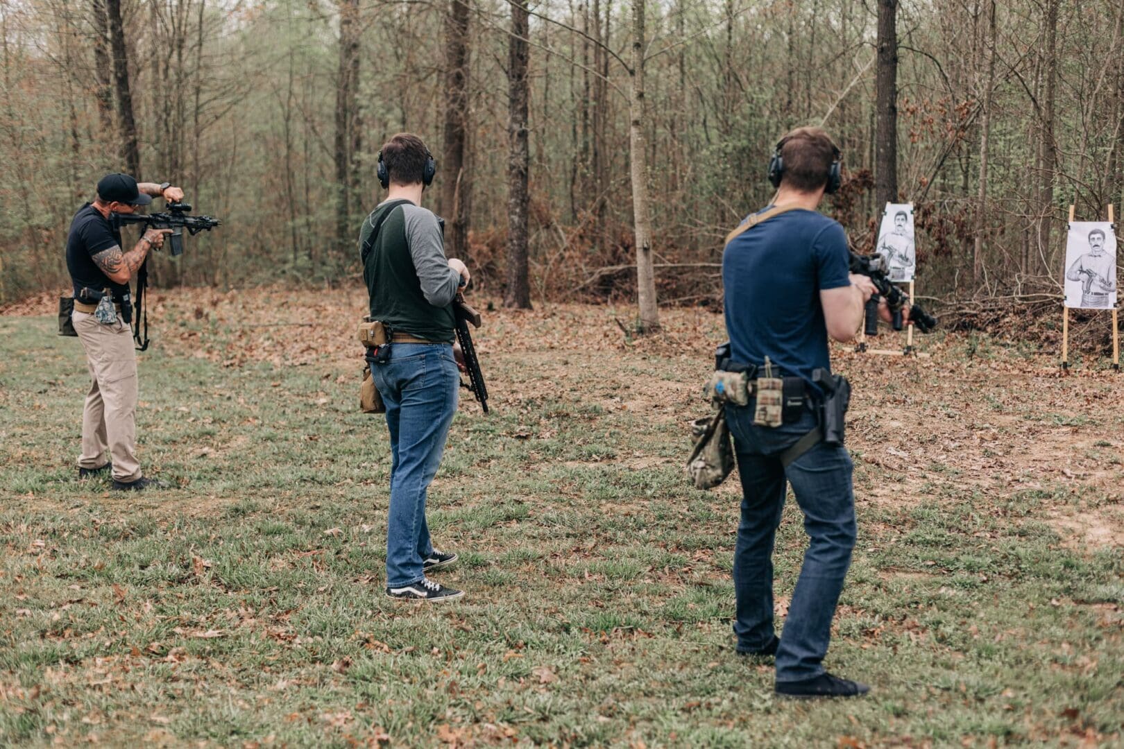 Two men are standing in the woods holding guns.