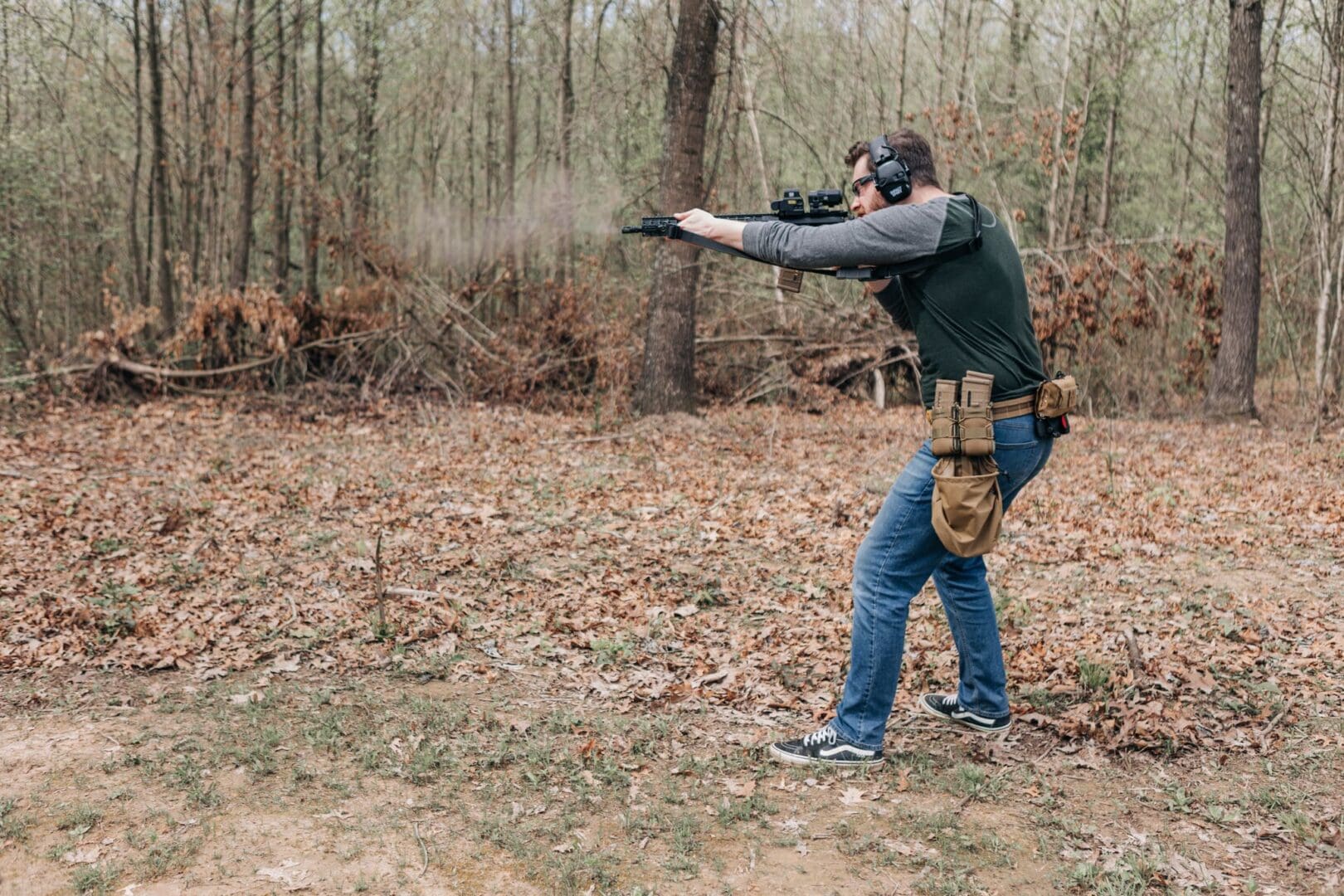 A man is shooting at something in the woods.