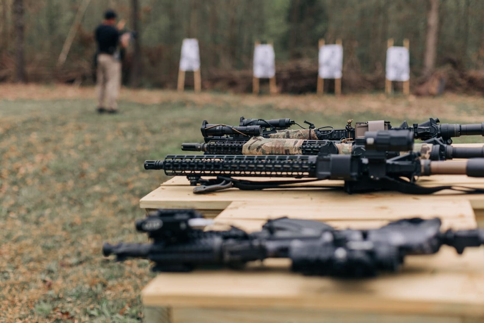 A man is standing in front of several guns.