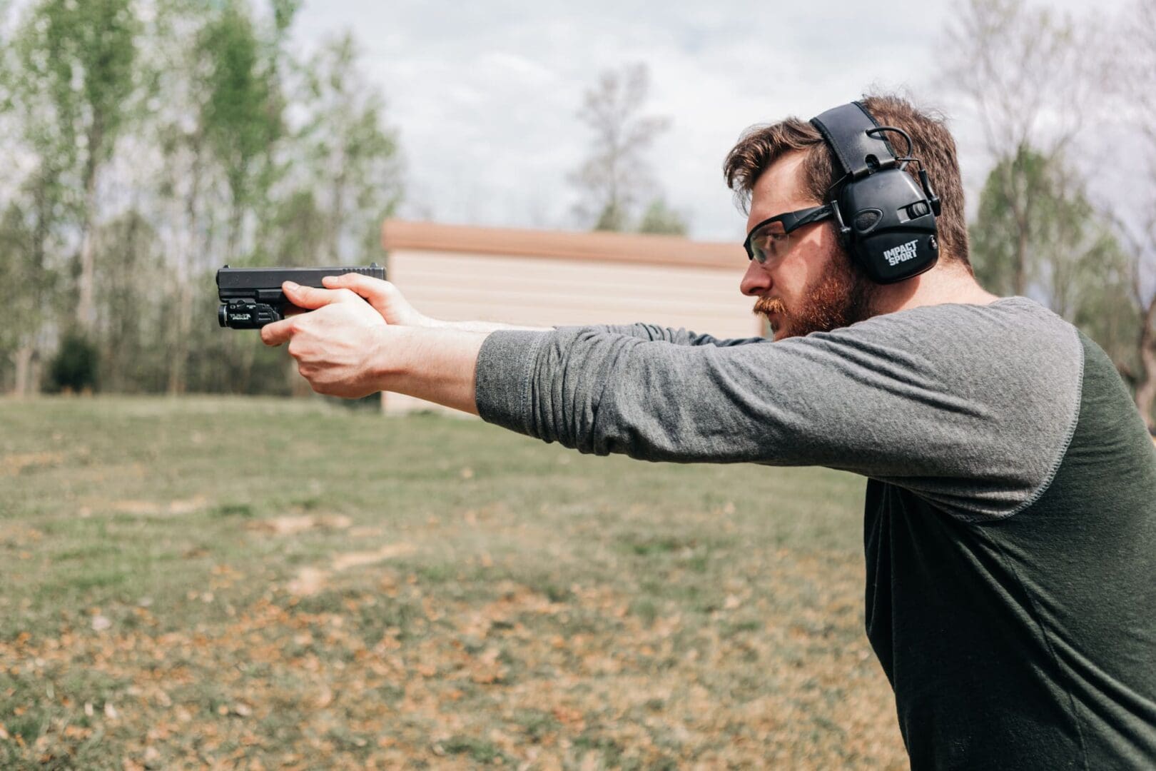 A man wearing ear protection and holding a gun.