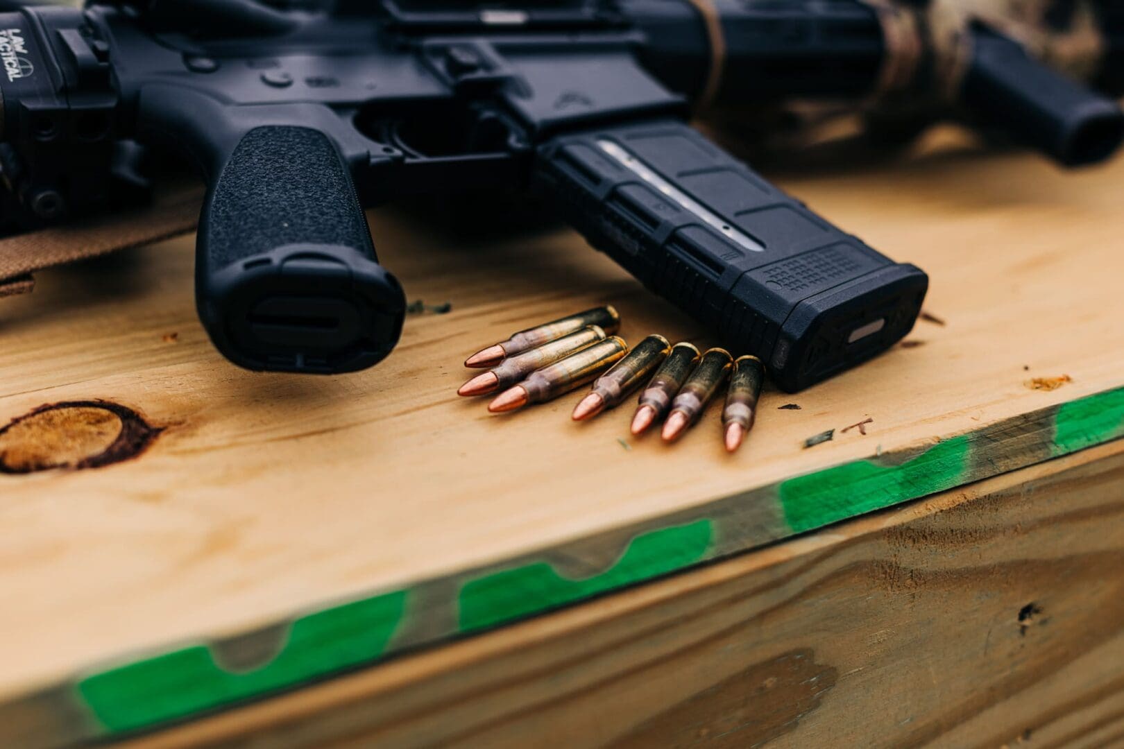 A gun and bullet shells on top of a wooden table.