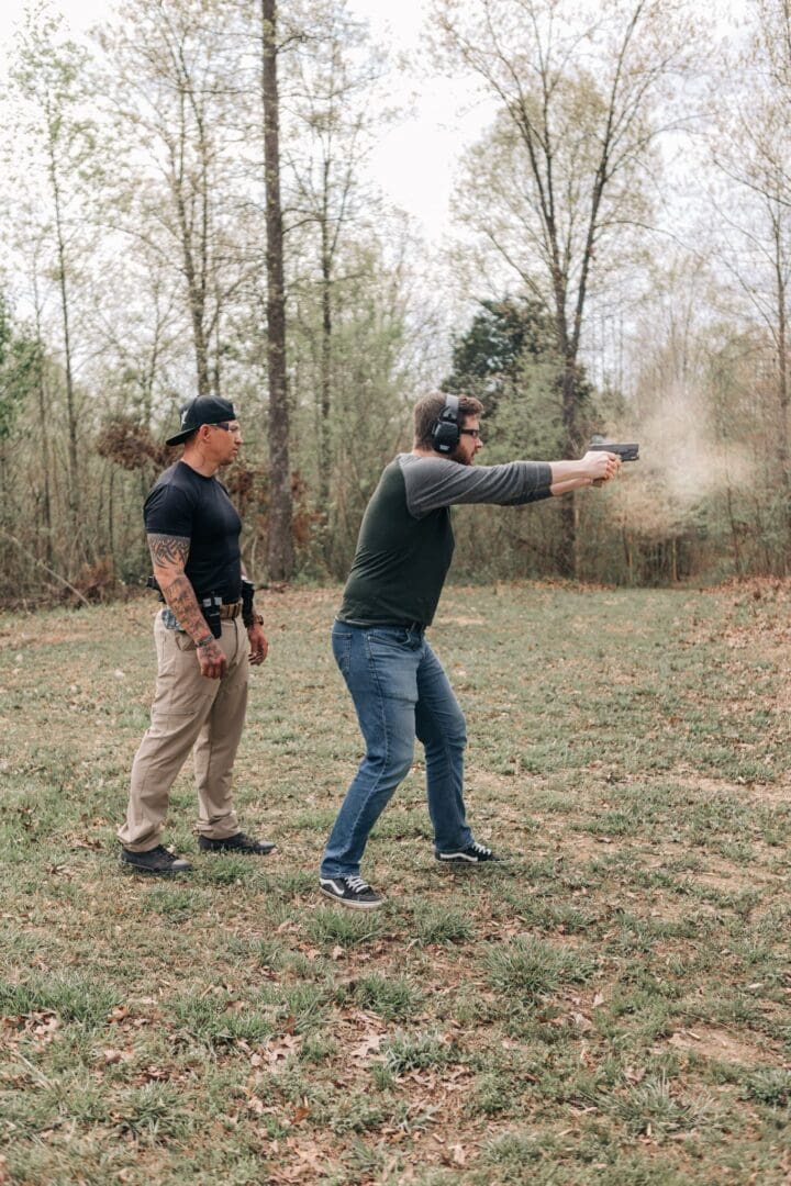 Two men are standing in a field with guns.