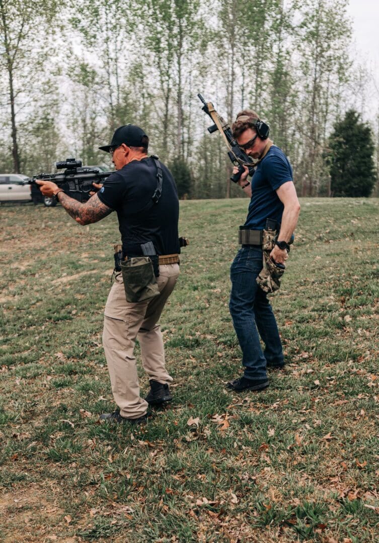 Two men are holding guns in a field.