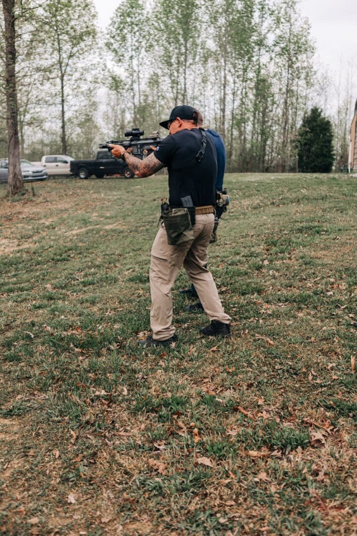 A man holding a gun in the grass.